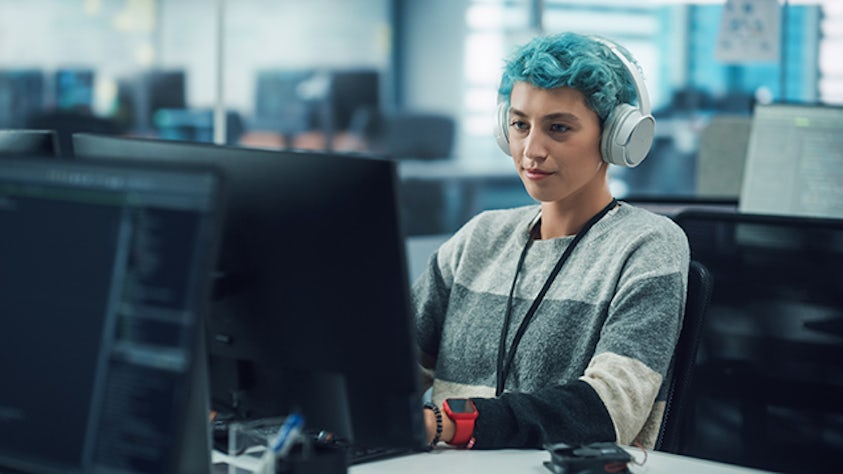 Person with blue hair working at a computer terminal.