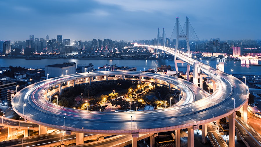 a bridge with a circular driveway over a river with a city in the background