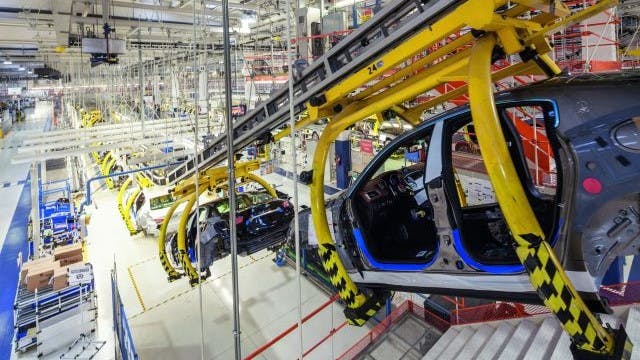 A car moves along a conveyor belt in a factory.