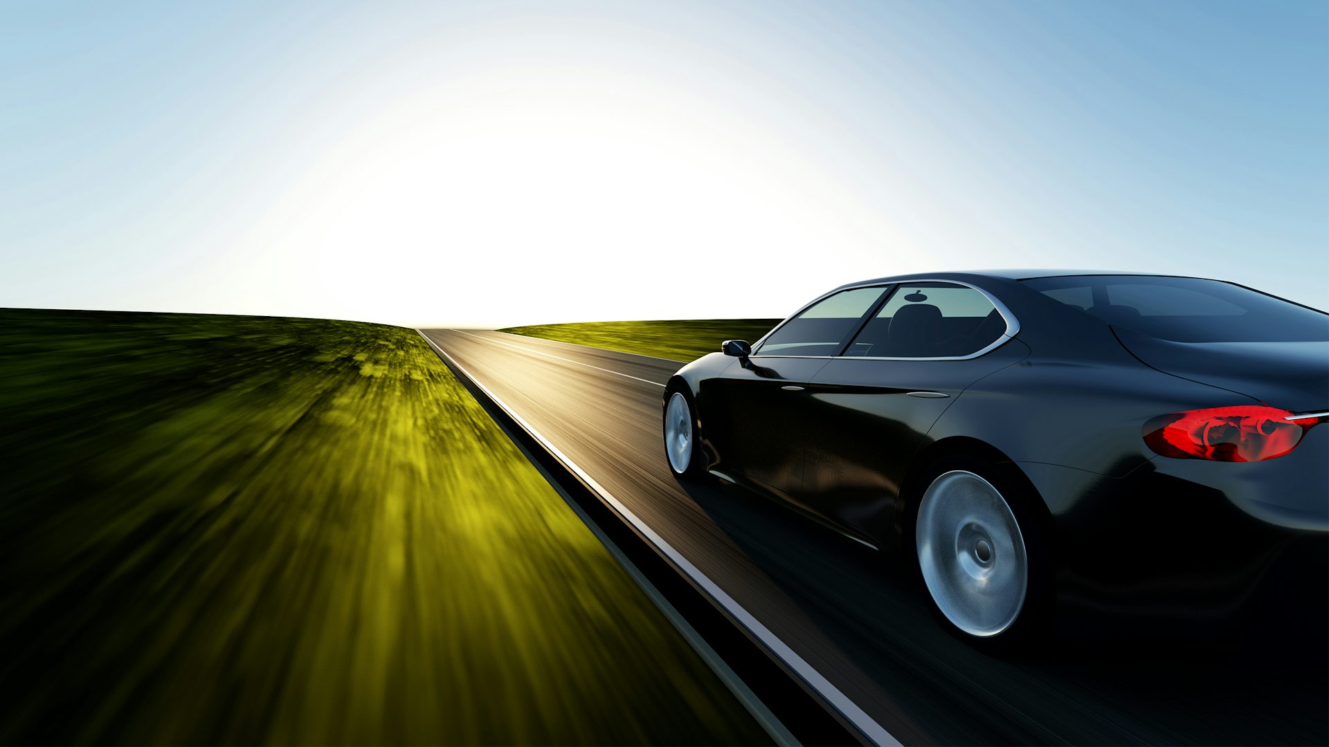 Side view of a fast-moving car on an open road with the sun on the horizon.