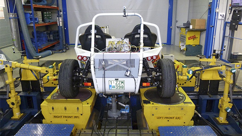 Vehicle on a shaker test bench in a laboratory setting.