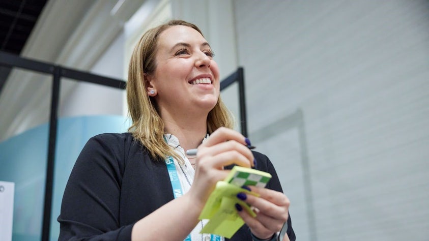 Woman holding posted notes while in the Innovation Hub at the Siemens Realize LIVE conference.