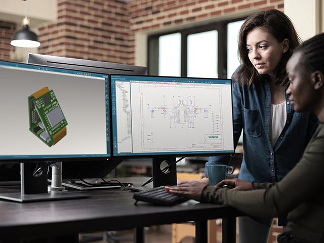Two engineers in front of dual computer monitors looking at the Xpedition Standard software.