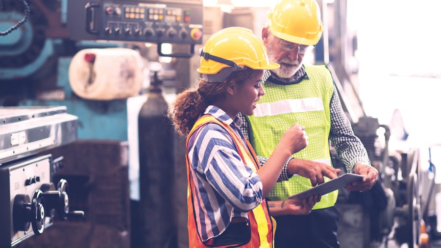Dos ingenieros de la planta de producción examinan una tablet para revisar su sistema de gestión de la calidad.