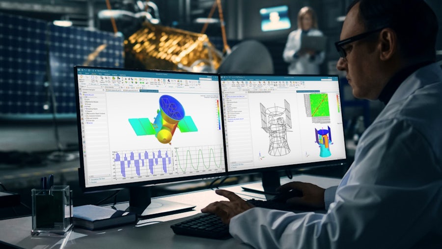 宇宙船エンジニアリングのためのSiemens Simcenterソフトウェアを表示する2台のコンピューター・モニターの前に座っている男性。