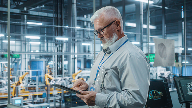 Hombre en una fábrica que consulta una tablet.