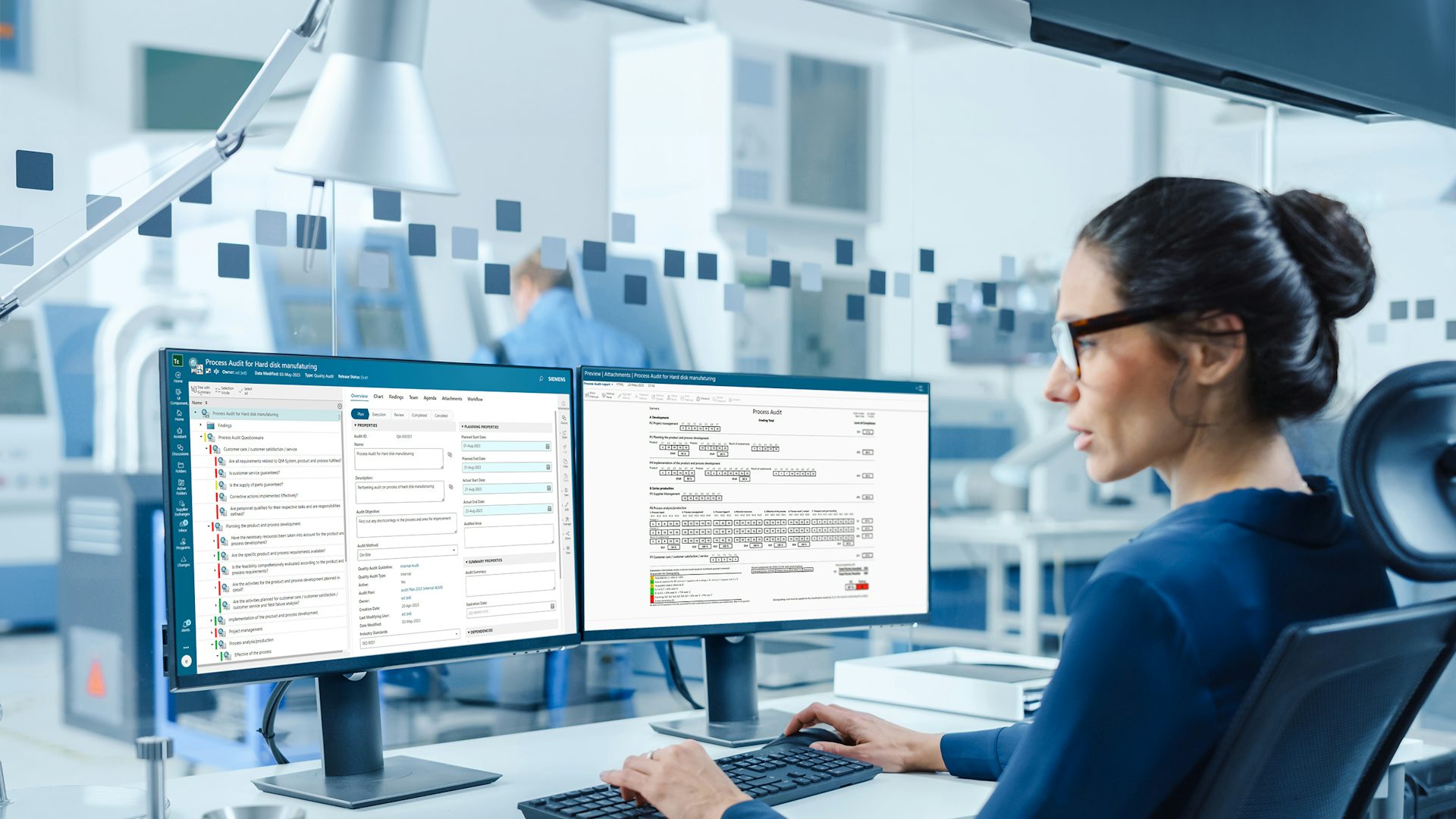 QMS software displayed on dual monitors in an office setting, showcasing a user interface with various data fields and menu options.