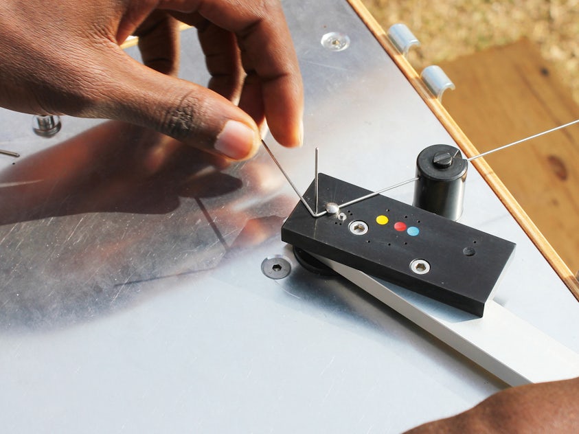 a hand operates a machine for bending reading glasses frames