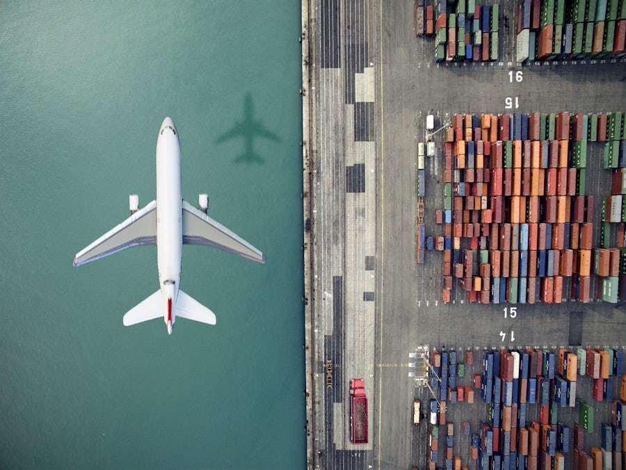 Airplane flying over container port