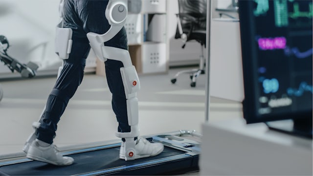 Legs of a person wearing a leg-exoskeleton suit, walking on a treadmill