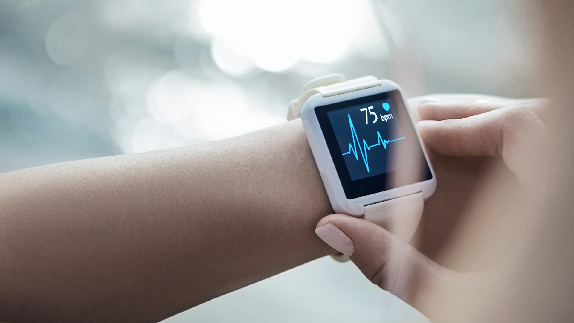 Image of a person's wrist wearing a smart watch displaying a heart monitor.