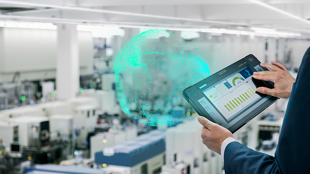 A person taps on a tablet computer with an open office in the background and a digital graphic of the globe in the foreground