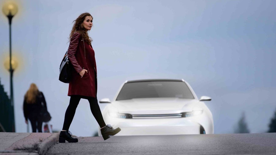 Woman crossing the street in front of an oncoming car.