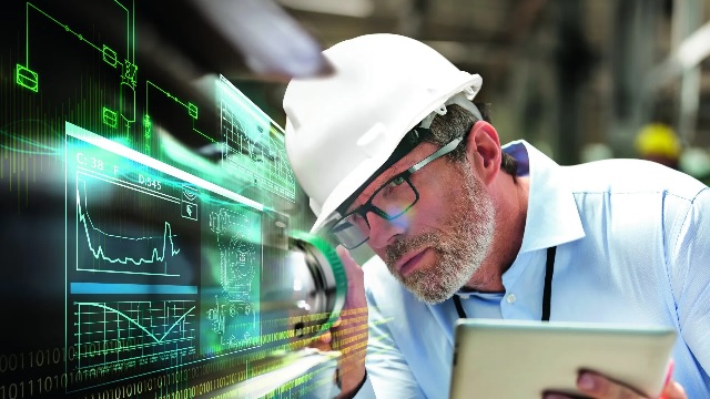 A man in a hardhat examines a machine.