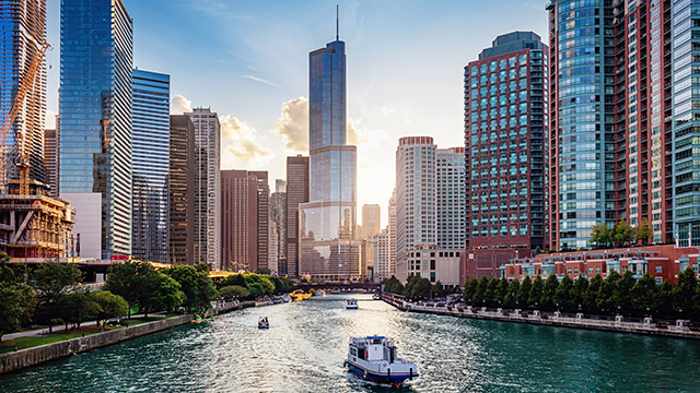 View of Chicago, Illinois from the Chicago River Waterfront at dusk. Small boats and tourist ferries cruising on the Chicago River towards the Michigan Lake.
