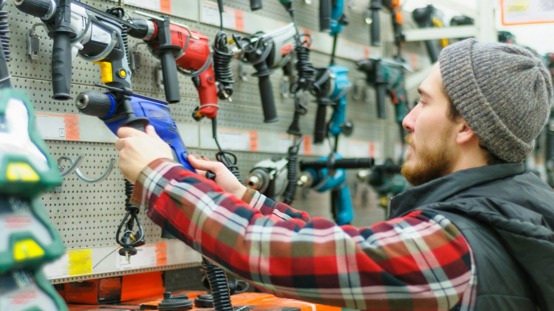 A man in a tool shop picking out a drill.