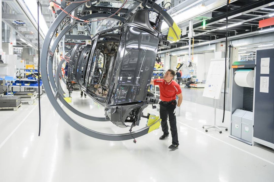 Automotive factory worker monitoring vehicle body on an automated assembly line.