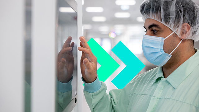 在走廊上穿着个人防护装备的人与墙上的屏幕互动。