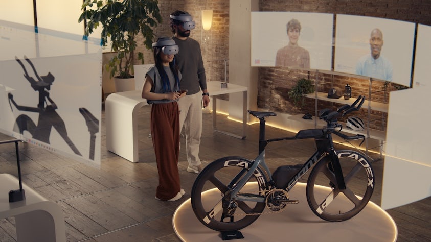 two engineers on a virtual video call while wearing Sony XR head-mounted display headsets and controllers to design a GIANT bike in Designcenter NX CAD Immersive Designer software. They can see a VR model of the bike design with everyone on the call