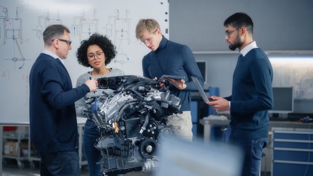 Group of business professionals inspecting an engine