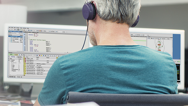 An engineer is using Questa Inspect tool on his desktop while wearing a headset.