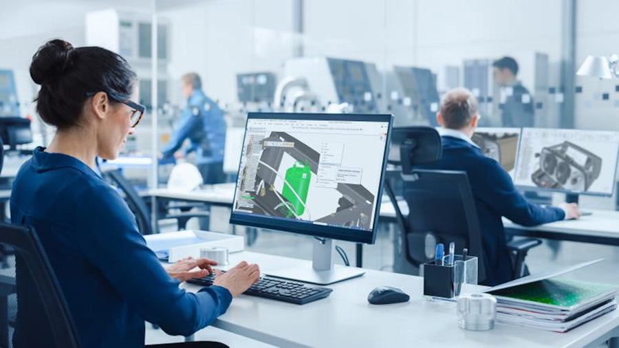 An engineer at her workstation uses CAD software to design an industrial machine component.