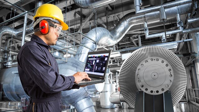 Worker inside a factory working on his laptop.