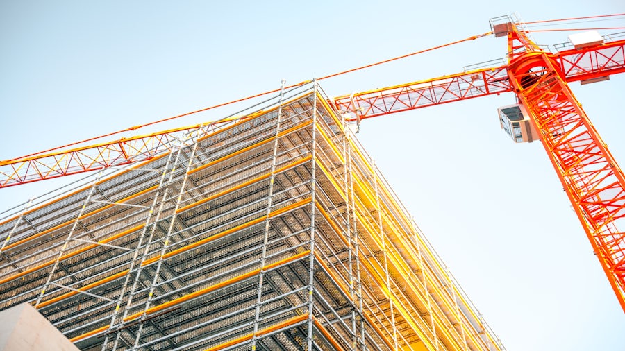 A multi-story building under construction with a crane in the background.