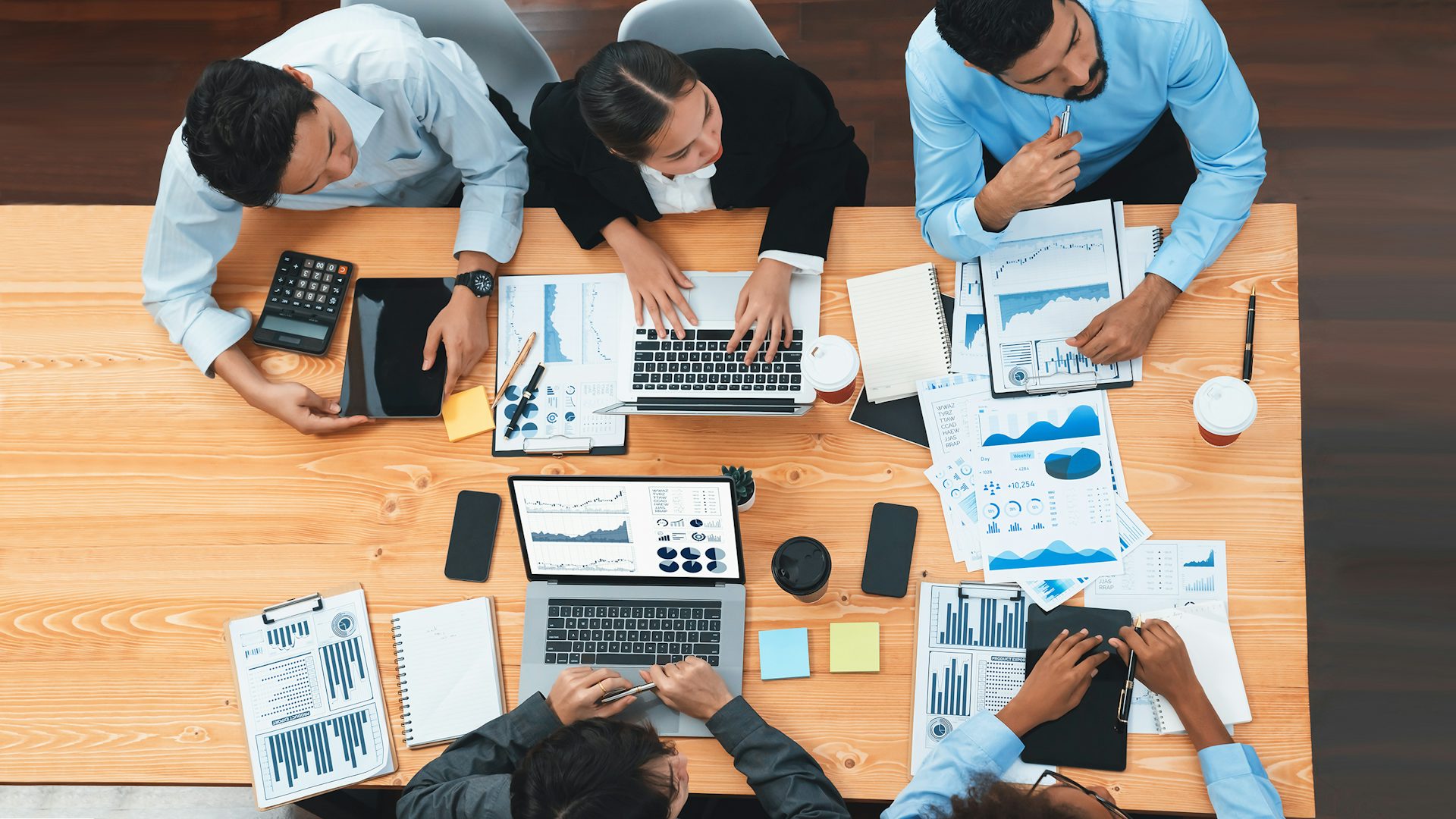 Vista panorámica de un escritorio con partners de tecnología frente a sus portátiles.