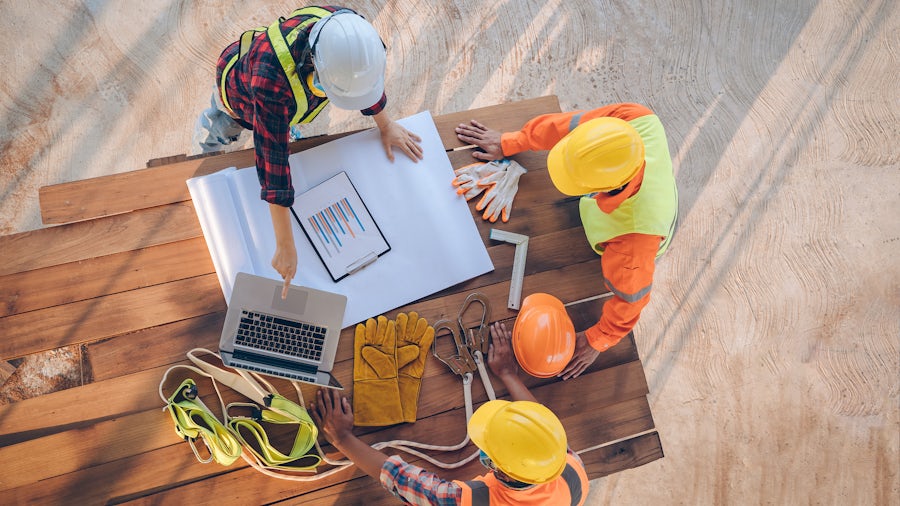 Group of heavy equipment engineers reviewing bill of materials documents 