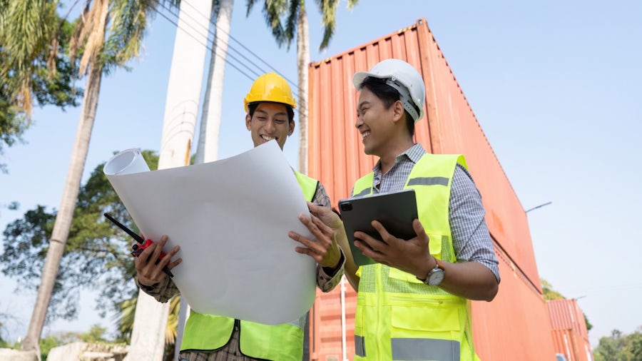 A multidisciplinary construction team reviewing digital plans and blueprints to improve collaboration and avoid project delays.