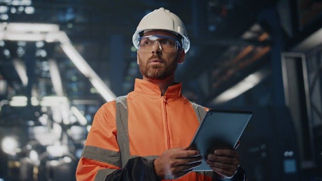Man in a factory holding a tablet.