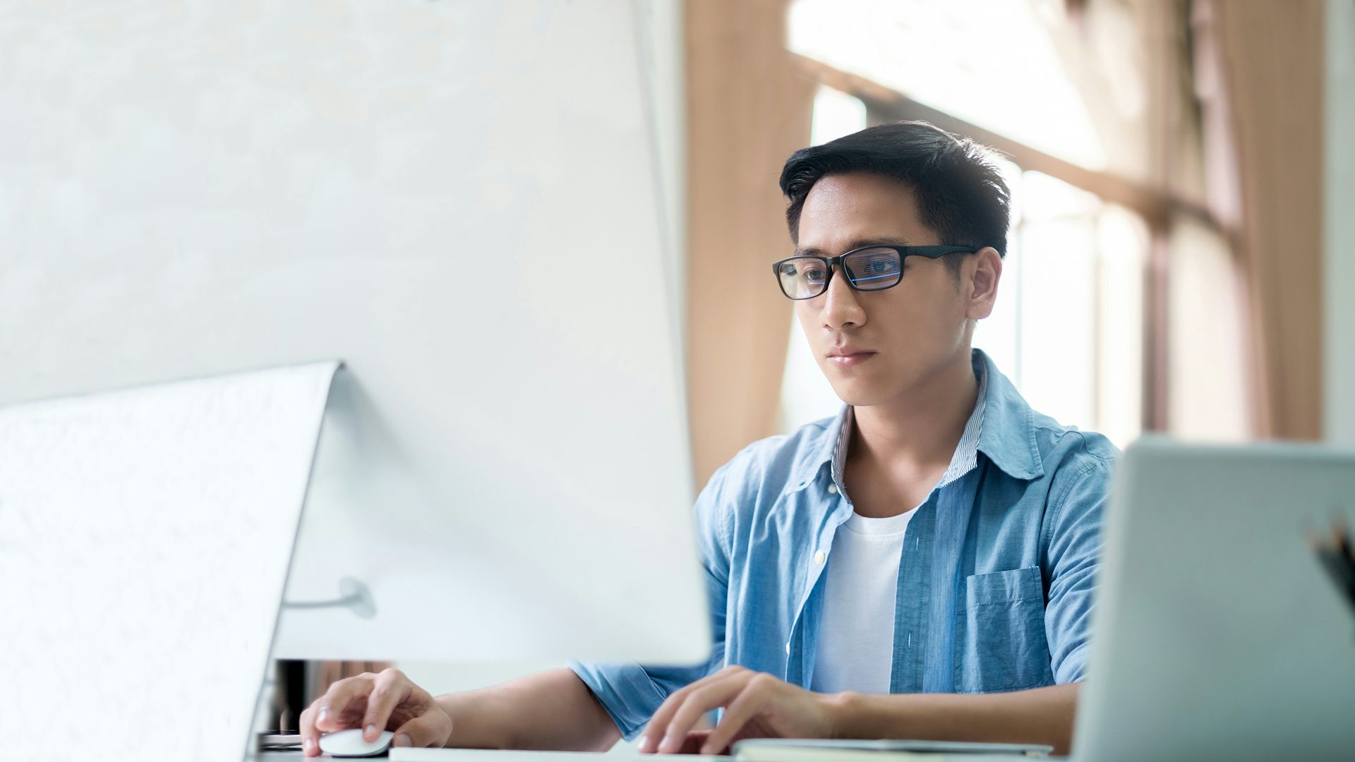 An e/e system data management engineer works at a desktop.