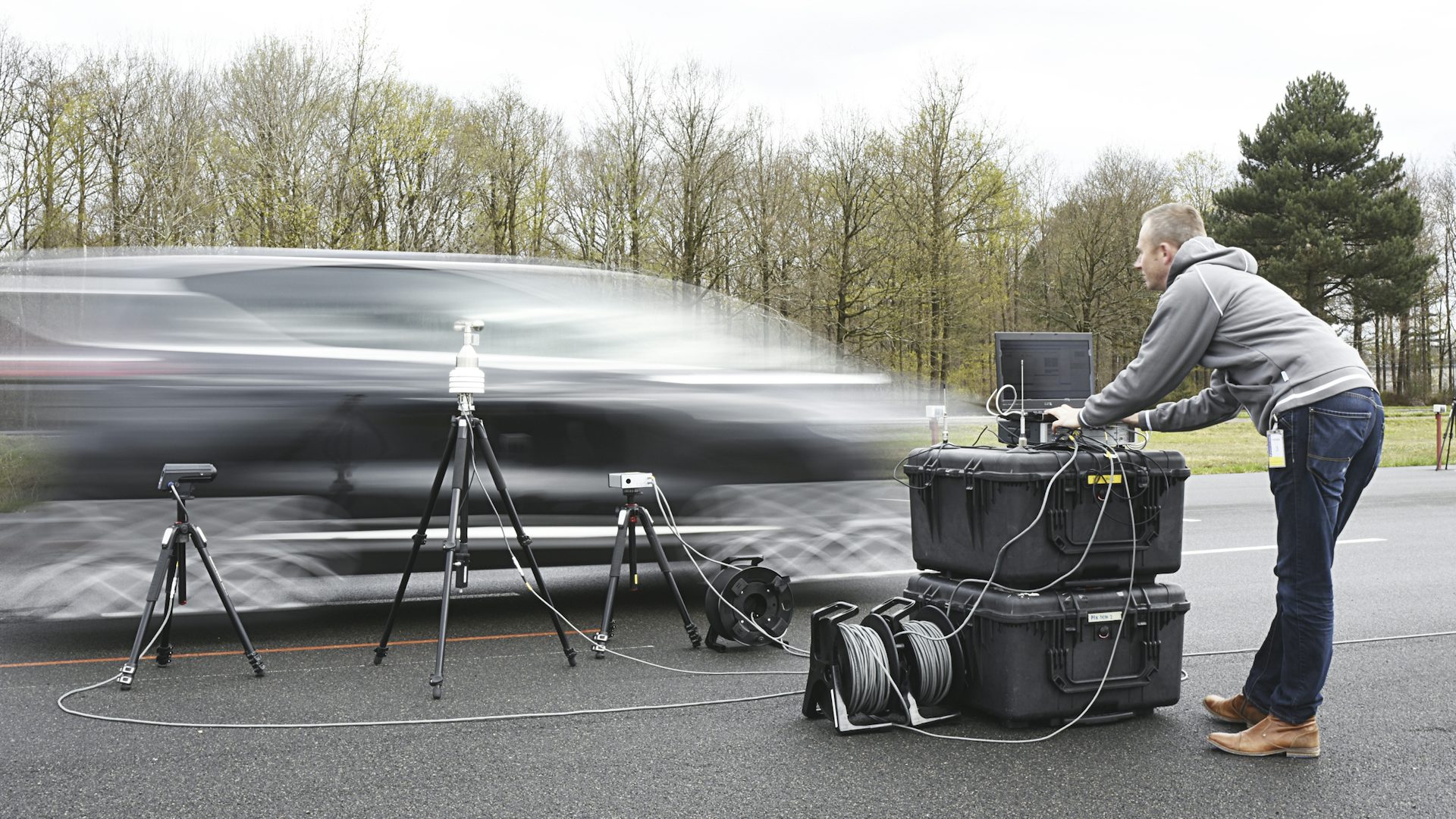 An engineer performing pass-by noise testing on a car passing through.