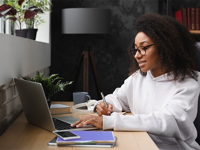 A student sitting at a desk writing something down.