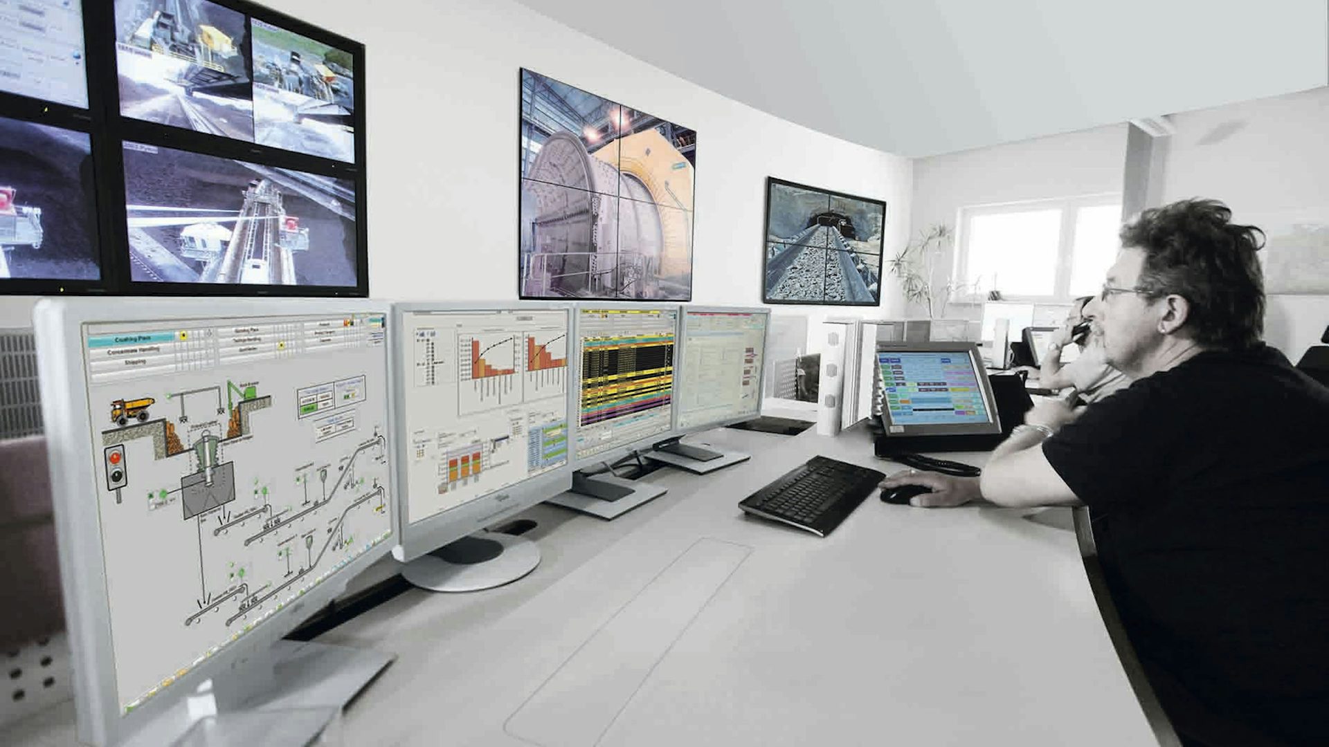 A mining company engineer using advanced software on a suite of connected computer monitors.