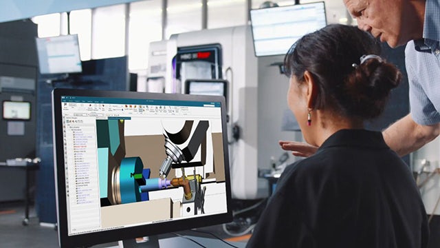 Mann und Frau in einer Produktionsanlage, die NX auf einem Computerbildschirm betrachten