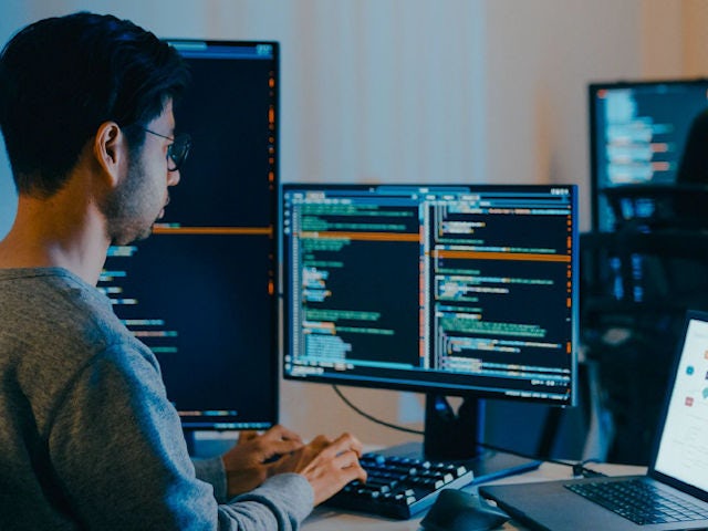 Engineer debugging a system on mutiple monitors.
