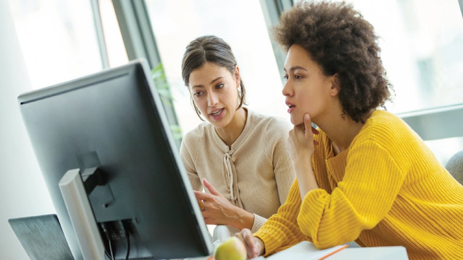 two women at monitor looking thoughful
