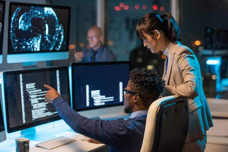 man pointing to monitor showing girl something on screen