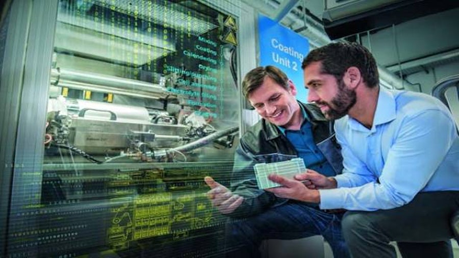 Smiling technicians in front of 3d printer with digital twin model.