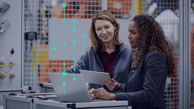 Two female engineers using a tablet and laptop in a plant.