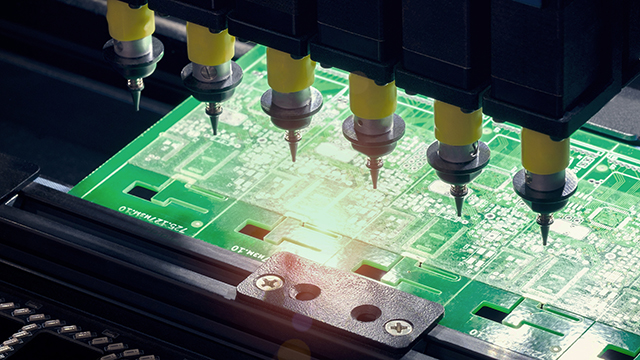 PCB in pick and place machine in electronics manufacturing factory.