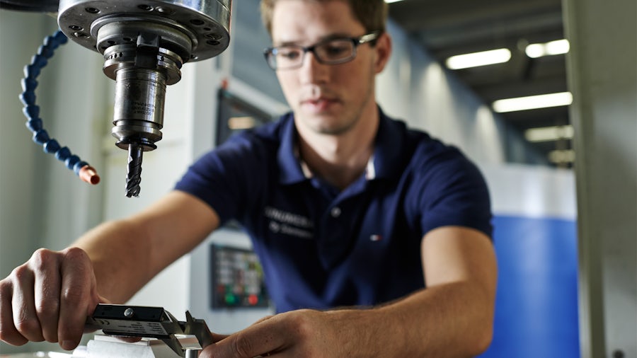 Technik ve strojírenské dílně měří kvalitu dílu na CNC stroji.