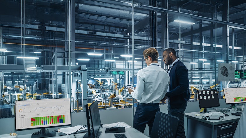 Two men in a factory looking at a tablet, scanning and analyzing data collected by their industrial IoT solution, Insights Hub.