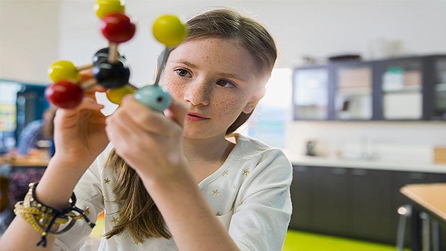 A child examines a model of a complex atom.