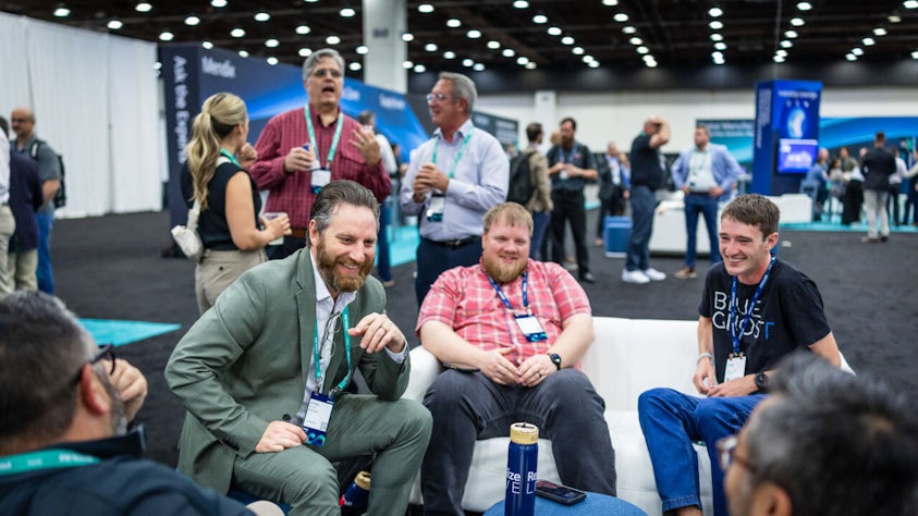 Three individuals sitting in the Siemens Realize LIVE Industry Lounge in the Solutions Center.