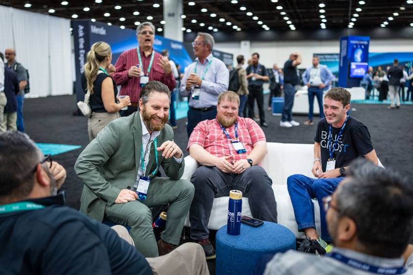 Three individuals sitting in the Siemens Realize LIVE Industry Lounge in the Solutions Center.