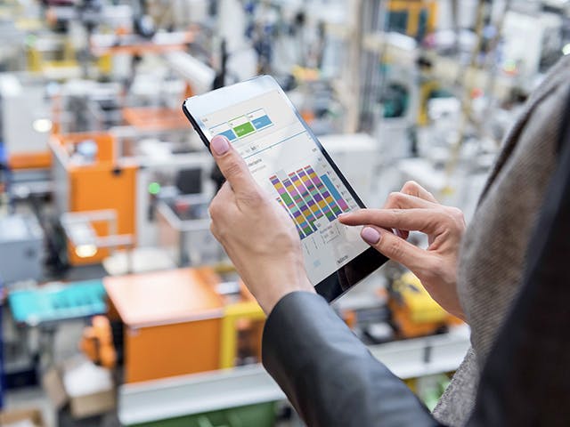 A person holds a tablet displaying a bar chart