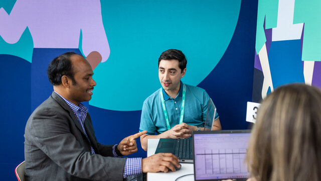 Two people having a one to one conversation sitting at a desk in the Innovation Hub.